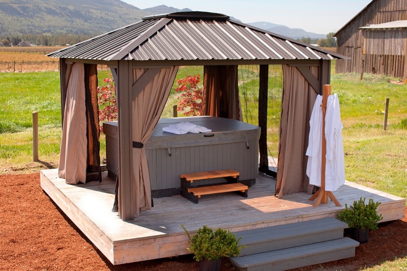 The side view of an open air Arctic Spas Gazebo Milano, with a hot tub inside